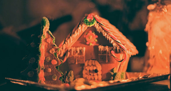 Beautiful gingerbread house with Christmas tree in orange lighting, showing creativity with candy cane roof.