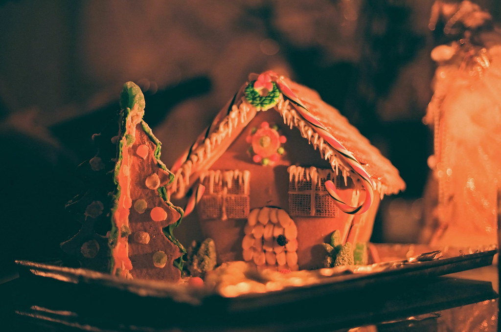 Beautiful gingerbread house with Christmas tree in orange lighting, showing creativity with candy cane roof.