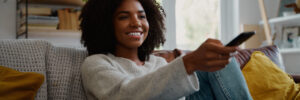A woman smiles as she watches TV.