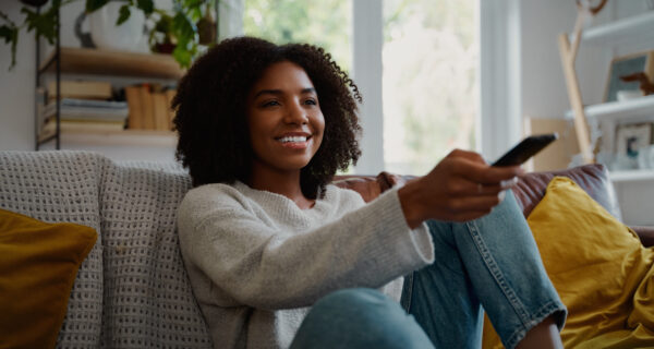 A woman smiles as she watches TV.